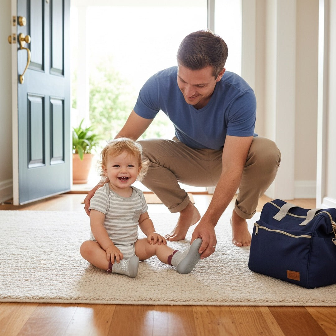 Dad slipping sock sneakers onto a toddler by the front door